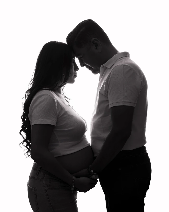 Sesión de embarazo en pareja con silueta iluminada en estudio.