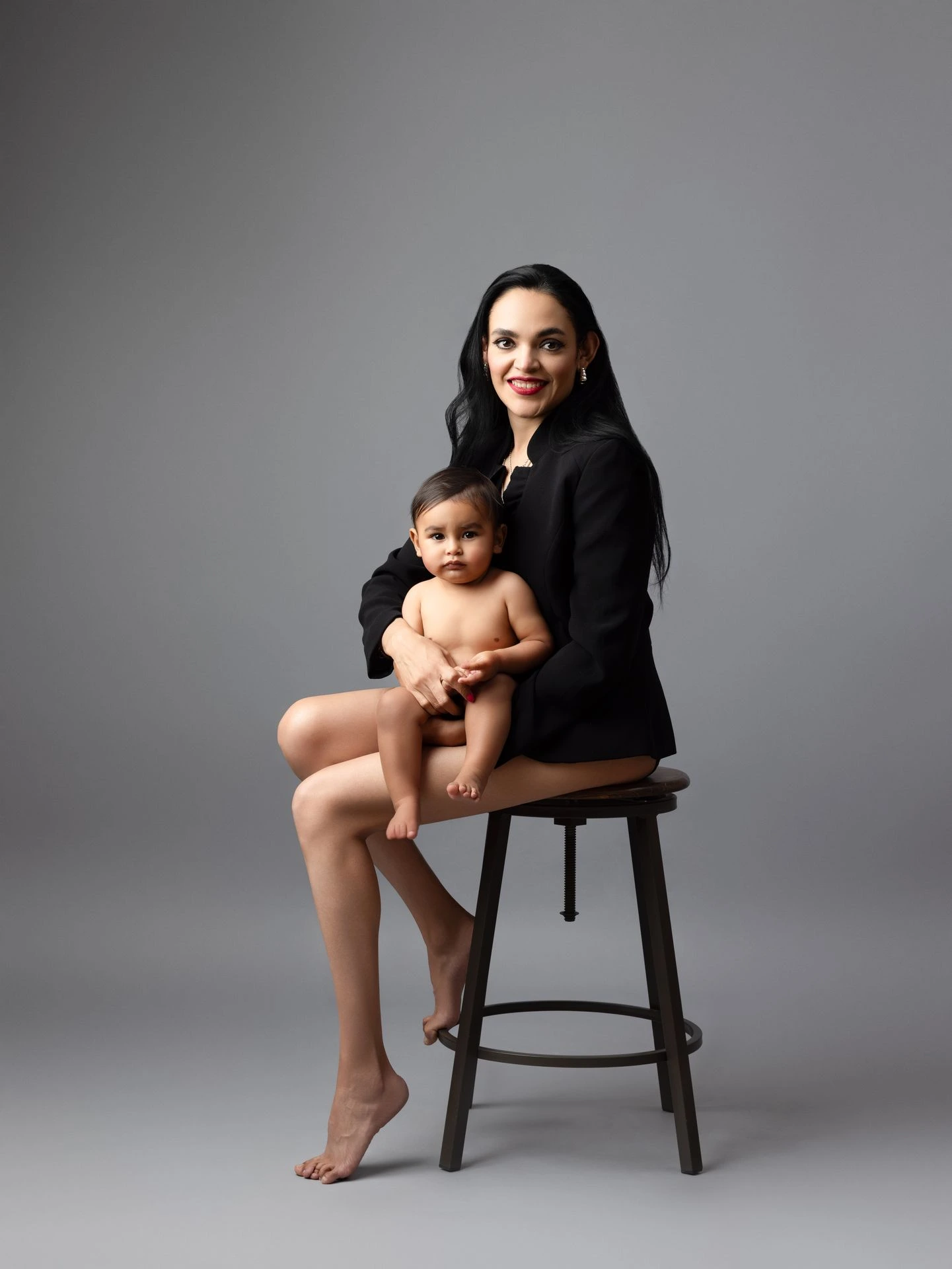 Sesión familiar de madre e hijo con fondo gris y estilo editorial.