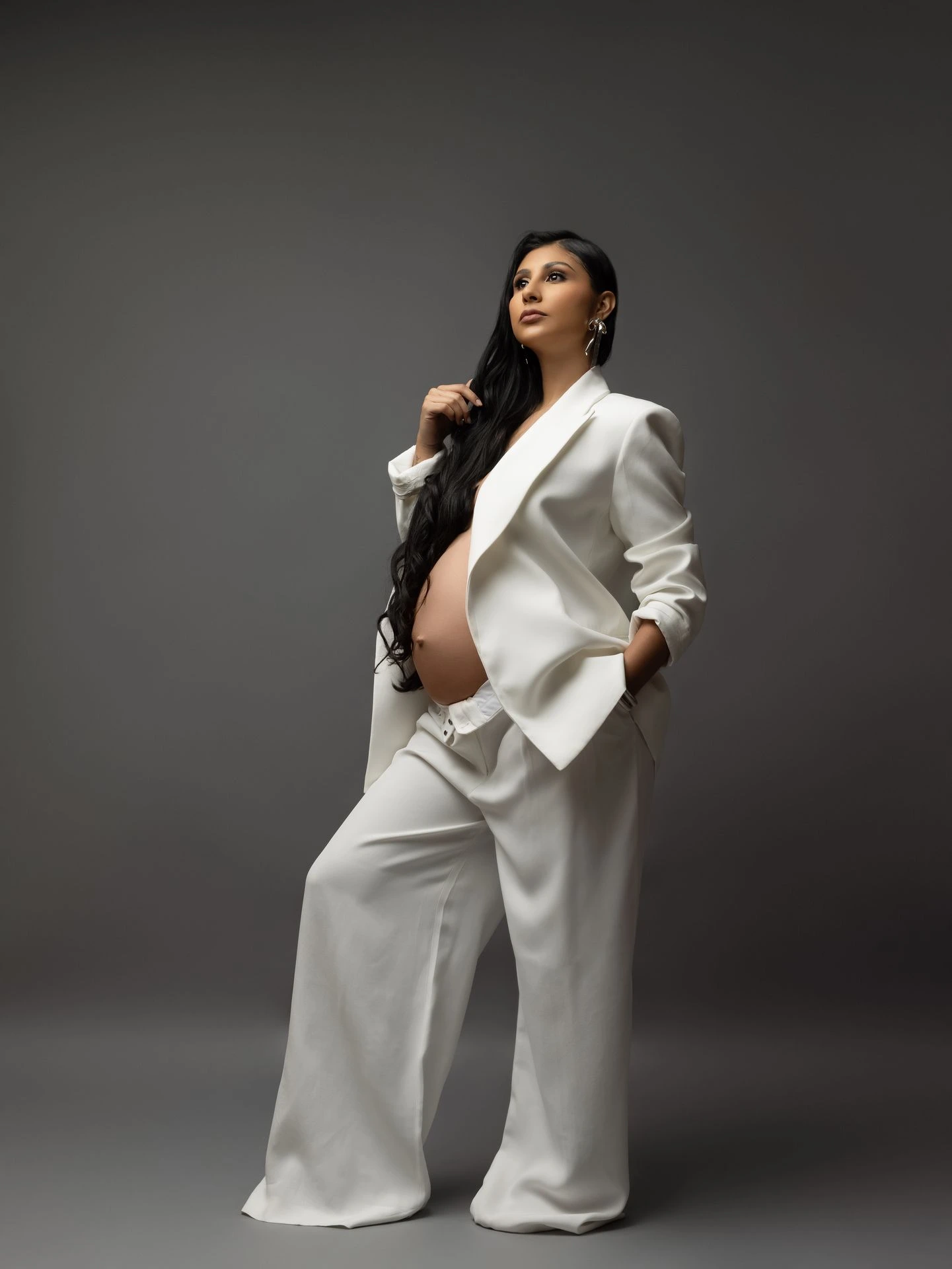 Retrato femenino editorial con traje blanco y pose elegante.