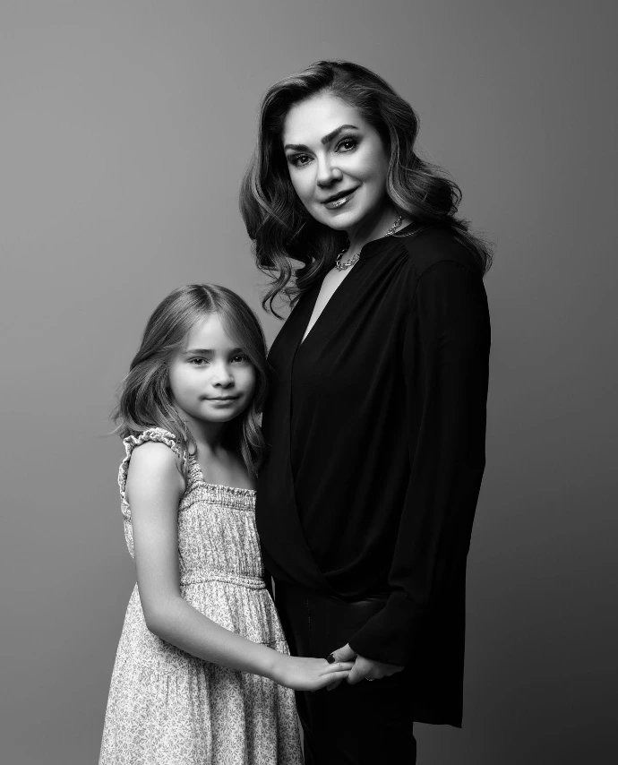 Madre abrazando a su hija durante una sesión fotográfica familiar en estudio.