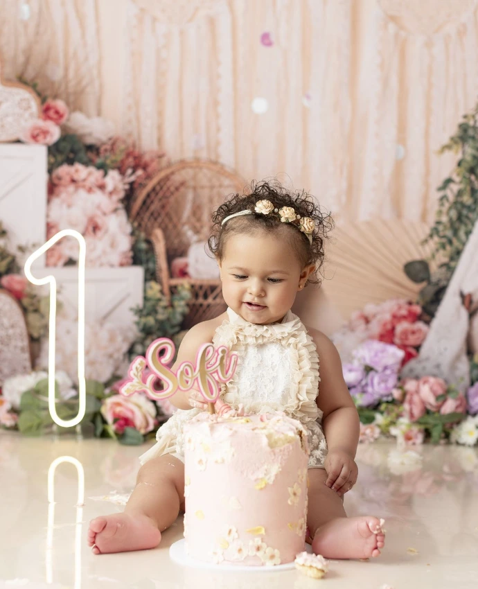 Bebé celebrando su primer cumpleaños durante una sesión Cake Smash con decoración rosa.