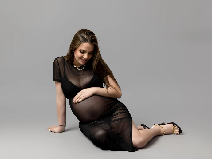 Retrato de embarazo con vestido transparente negro en estudio boutique.