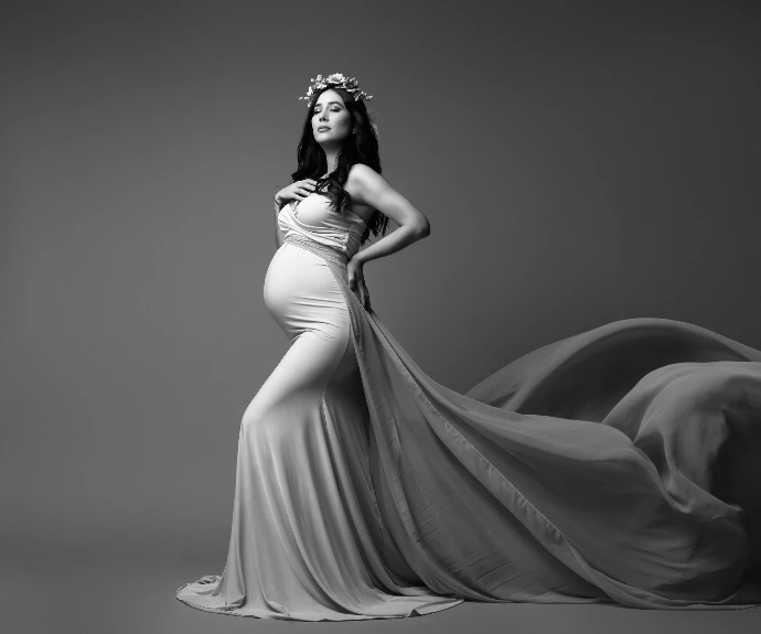 Fotografía artística de embarazo con vestido fluido en estudio.