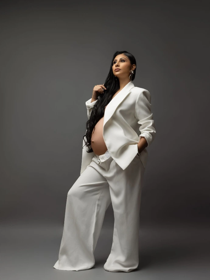 Fotografía de maternidad con traje blanco y estilo editorial.